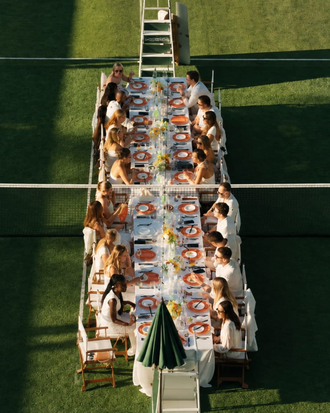 A long dinner table laid out across a grass court