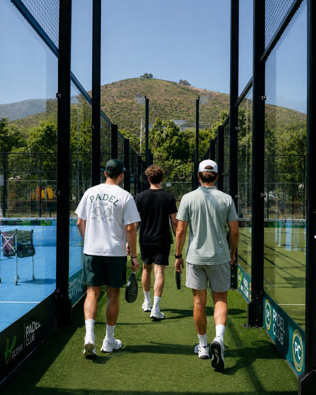 Three players walking onto a padel court together